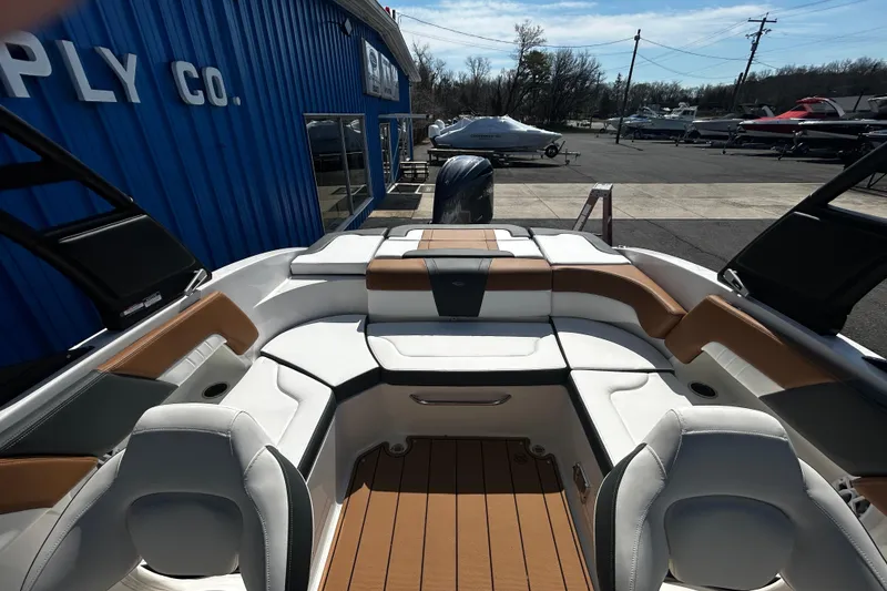 Slide: The Image of 2026 Chaparral 23 SSi OB boat interior with white and tan seating at a dealership. - 19