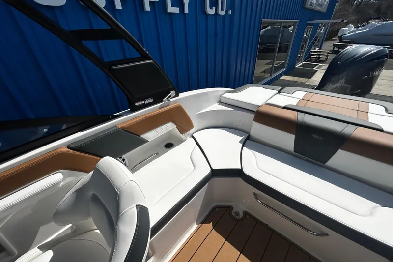 Slide: The Image of 2026 Chaparral 23 SSi OB boat interior with white and brown seating, docked near blue building. - 20