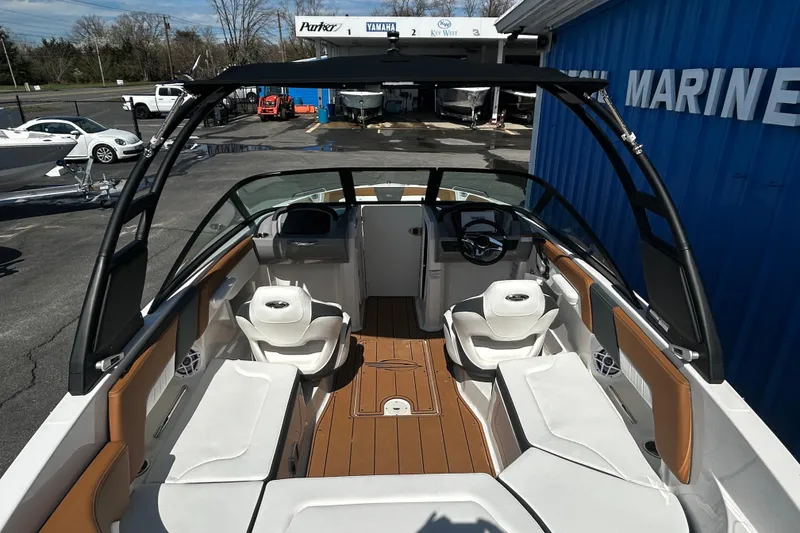 Slide: The Image of 2026 Chaparral 23 SSi OB boat interior with seating and steering wheel, docked outdoors. - 25