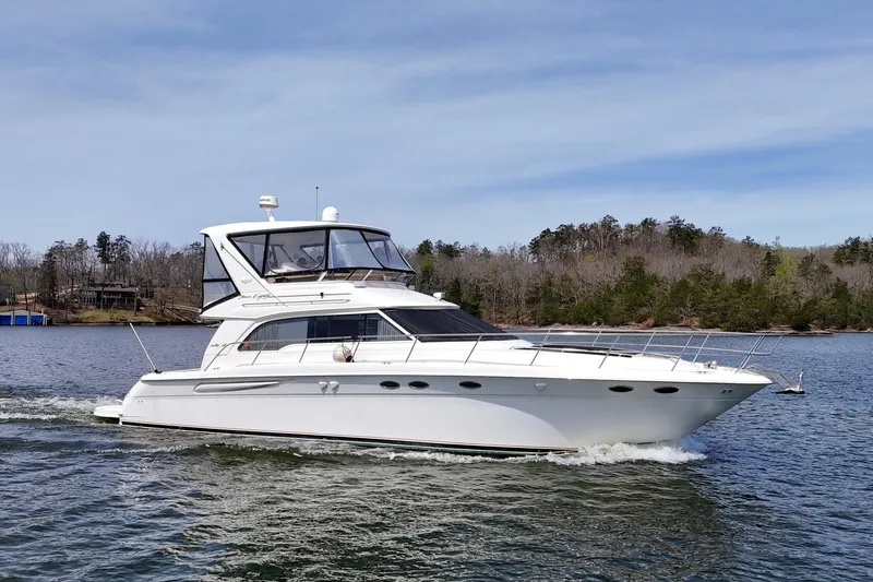 The Image of 1999 Sea Ray 480 Sedan Bridge yacht cruising on a serene lake. - 0