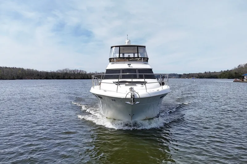 Slide: The Image of 1999 Sea Ray 480 Sedan Bridge cruising on a calm river under a clear sky. - 10