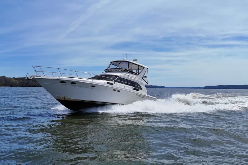 Slide: The Image of 1999 Sea Ray 480 Sedan Bridge cruising on open water under a clear sky. - 13