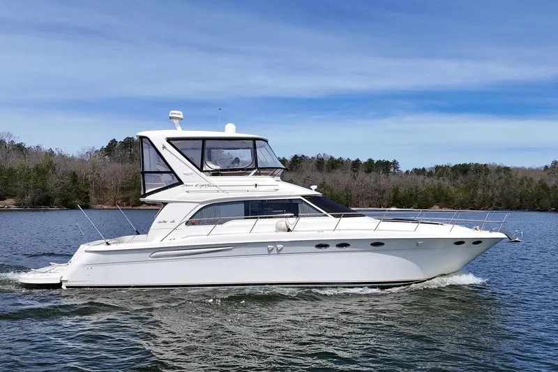 Slide: The Image of 1999 Sea Ray 480 Sedan Bridge yacht cruising on a serene lake. - 4