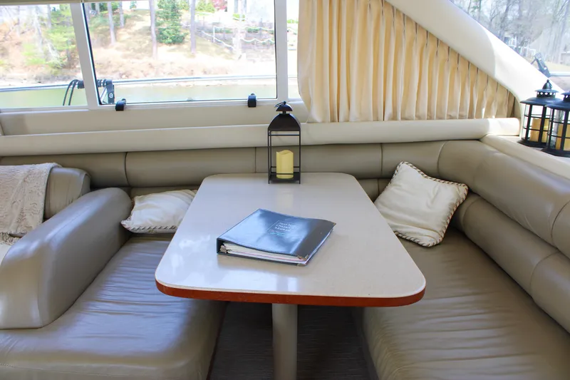 Slide: The Image of Luxurious interior of 1999 Sea Ray 480 Sedan Bridge with cozy seating and table. - 46