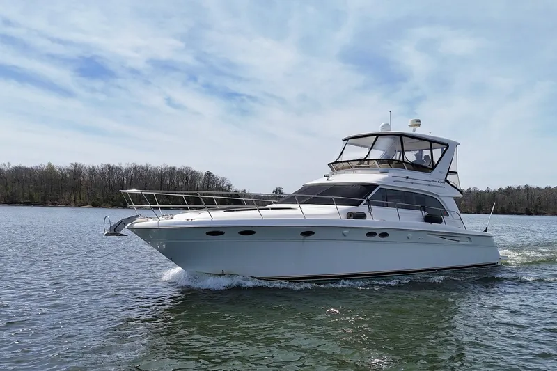Slide: The Image of 1999 Sea Ray 480 Sedan Bridge yacht cruising on a calm lake under a clear sky. - 5