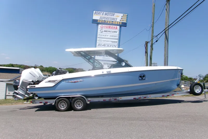 The Image of 2026 Monterey Elite 30 OB boat on trailer at dealership, clear sky background. - 1