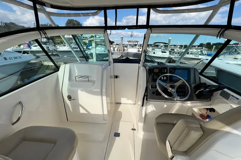 Slide: The Image of 2015 Pursuit DC 265 Dual Console boat interior with steering wheel and dashboard at marina. - 6