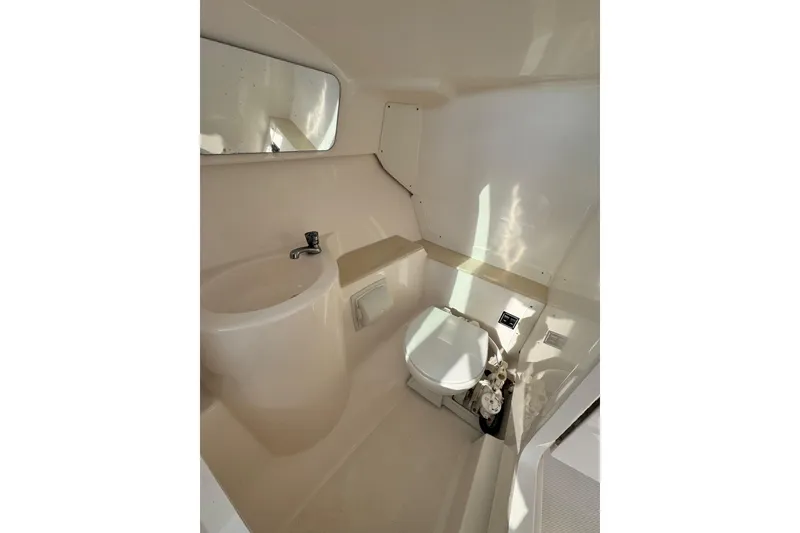 Slide: The Image of Interior of 2015 Pursuit DC 265 Dual Console boat bathroom with sink and toilet. - 7