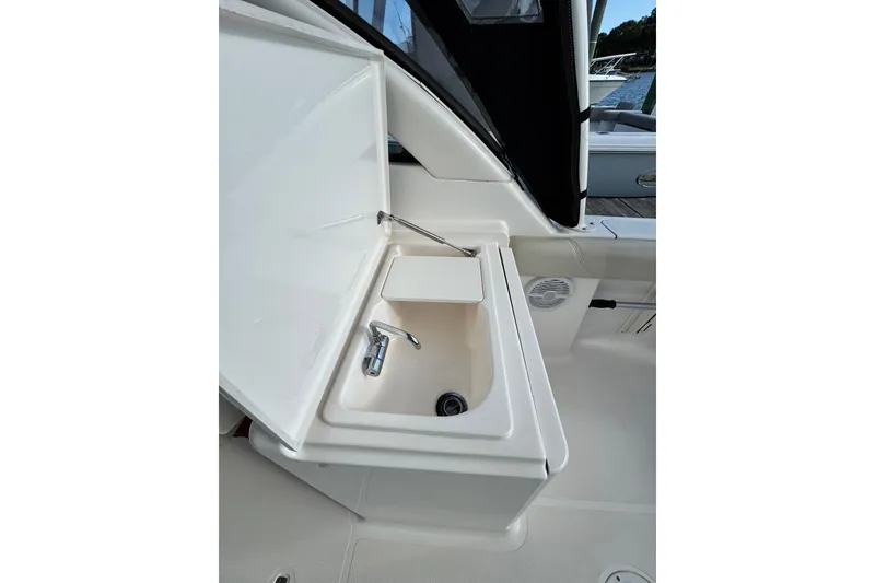 Slide: The Image of 2015 Pursuit DC 265 Dual Console boat sink with open lid and faucet. - 8
