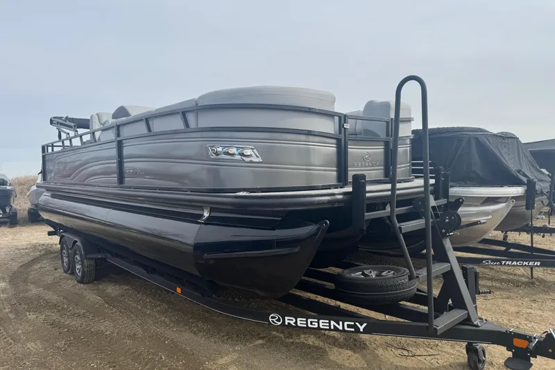 Slide: The Image of 2024 Regency 250 DL3 pontoon boat on trailer, parked outdoors. - 2