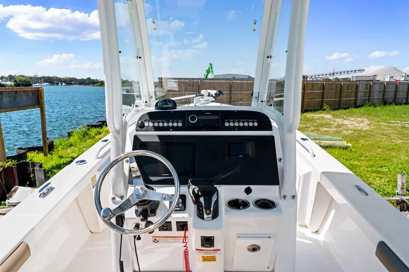 Slide: The Image of 2023 Everglades 243 Center Console boat dashboard with steering wheel, near waterfront. - 11