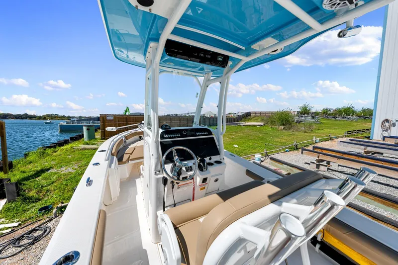 Slide: The Image of 2023 Everglades 243 Center Console boat with blue canopy, docked by a scenic waterfront. - 16