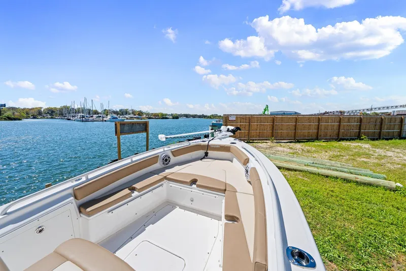 Slide: The Image of 2023 Everglades 243 Center Console boat docked by a scenic waterfront under a clear blue sky. - 24