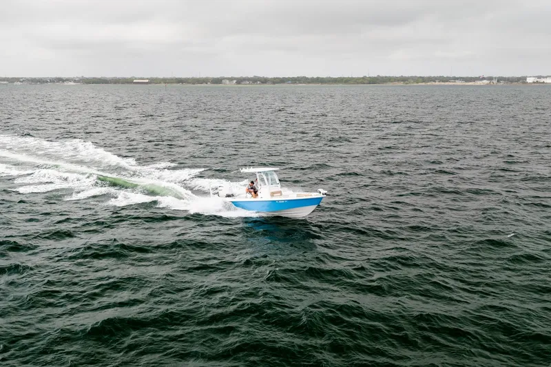 Slide: The Image of 2023 Everglades 243 Center Console boat cruising on open water under cloudy skies. - 42