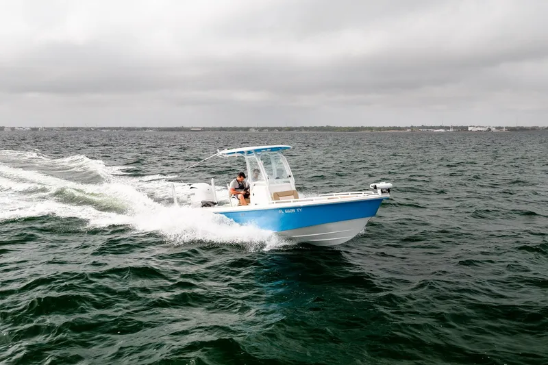 Slide: The Image of 2023 Everglades 243 Center Console boat cruising on open water under cloudy skies. - 50