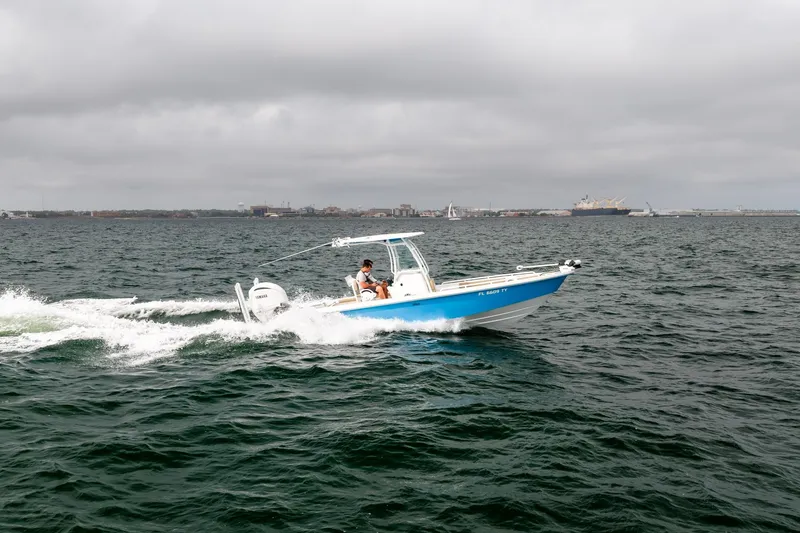 Slide: The Image of 2023 Everglades 243 Center Console boat cruising on open water under cloudy skies. - 51