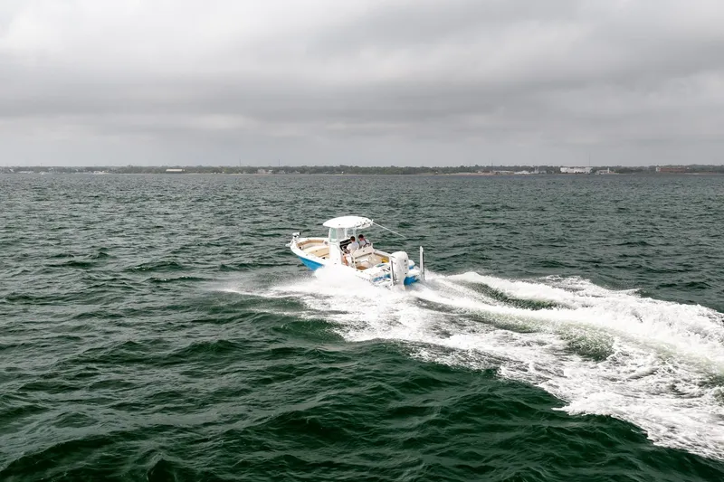 Slide: The Image of 2023 Everglades 243 Center Console boat cruising on open water under cloudy skies. - 58