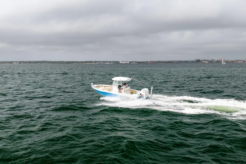 Slide: The Image of 2023 Everglades 243 Center Console boat cruising on open water under cloudy skies. - 59