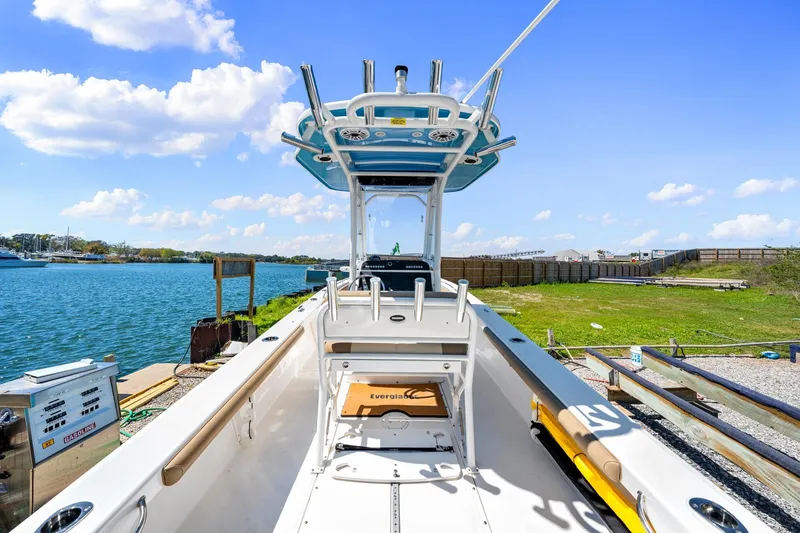 Slide: The Image of 2023 Everglades 243 Center Console boat docked by a scenic waterfront under a clear blue sky. - 6
