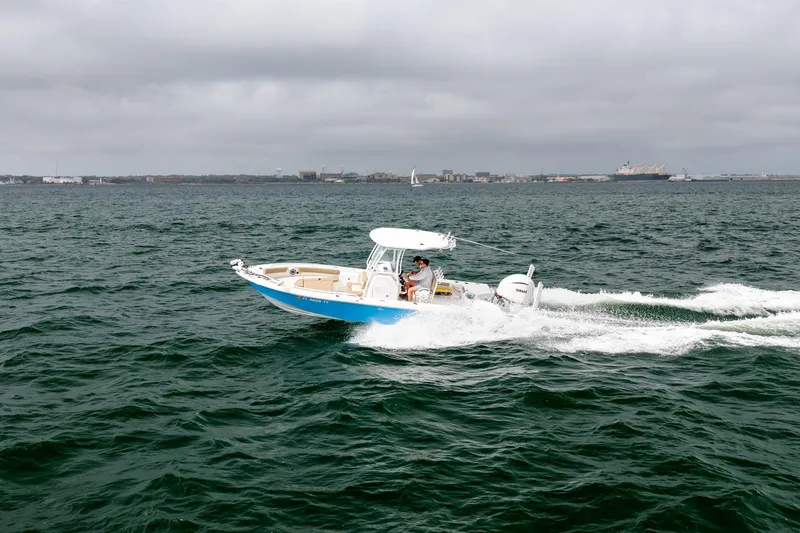 Slide: The Image of 2023 Everglades 243 Center Console boat cruising on open water under cloudy skies. - 60
