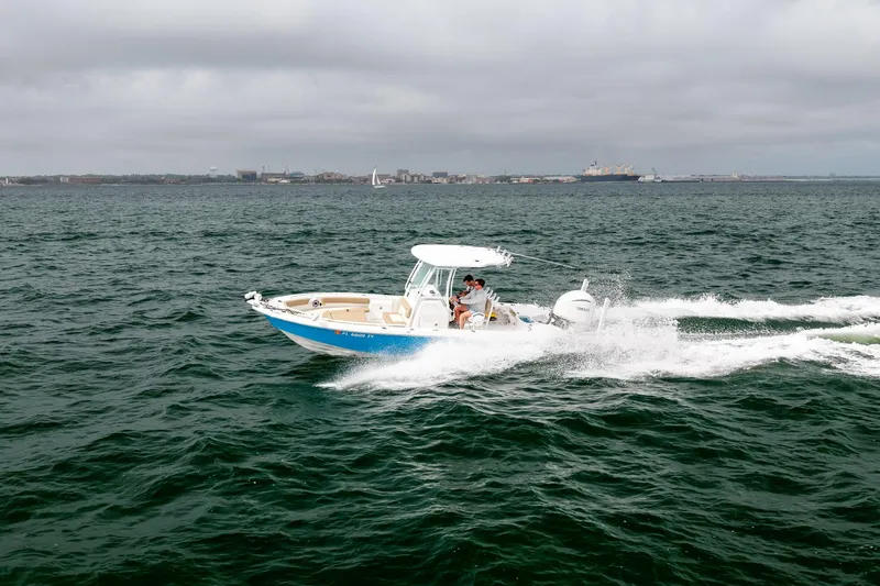 Slide: The Image of 2023 Everglades 243 Center Console boat cruising on open water under cloudy skies. - 61