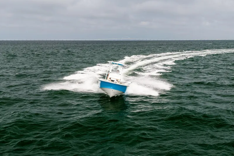Slide: The Image of 2023 Everglades 243 Center Console boat cruising on open water, leaving a wake trail. - 64