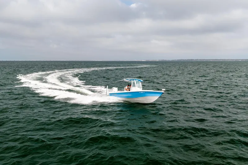 Slide: The Image of 2023 Everglades 243 Center Console boat cruising on open water under cloudy skies. - 65