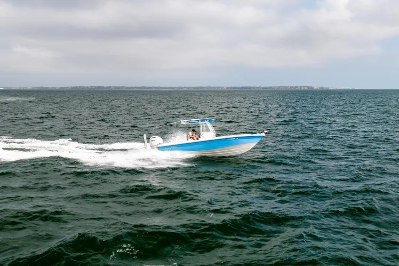 Slide: The Image of 2023 Everglades 243 Center Console boat cruising on open water under cloudy skies. - 66