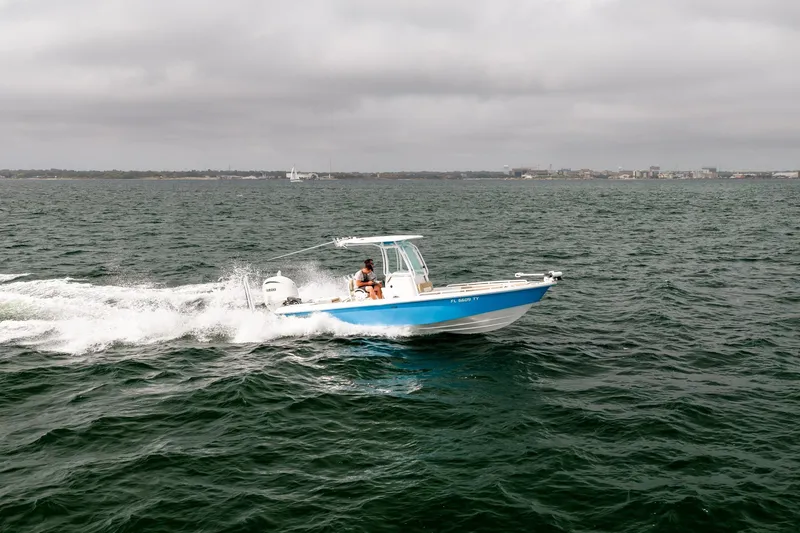 Slide: The Image of 2023 Everglades 243 Center Console boat cruising on open water under cloudy skies. - 80