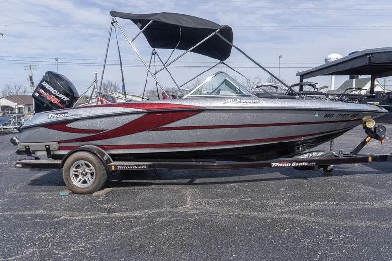 Slide: The Image of 2012 Triton 190 SE boat with trailer, featuring a sleek design and canopy. - 2