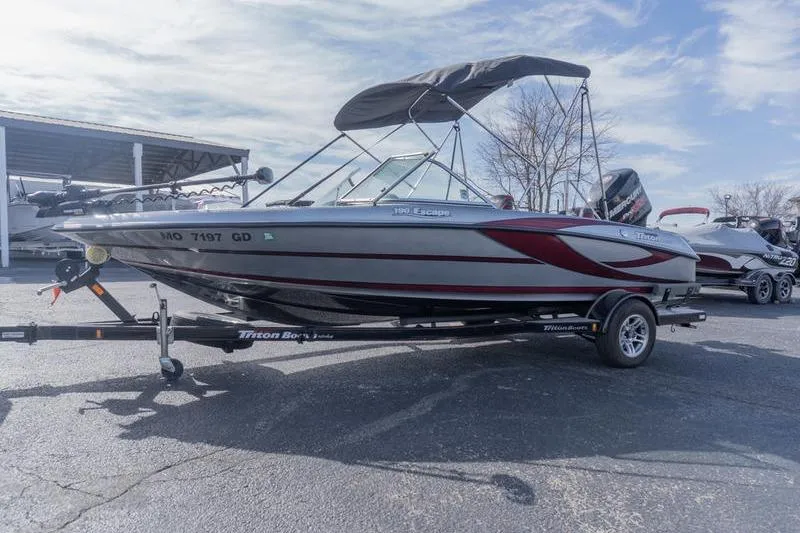 Slide: The Image of 2012 Triton 190 SE boat with canopy on trailer, parked outdoors. - 3