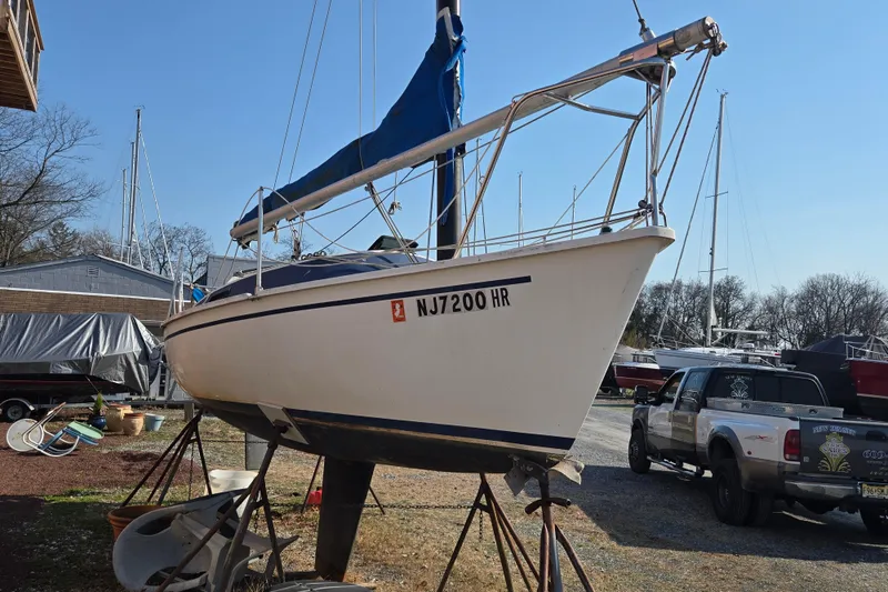 Slide: The Image of 1983 Tillotson-Pearson 21 Freedom sailboat on stands, with blue sail cover, in a boatyard. - 3