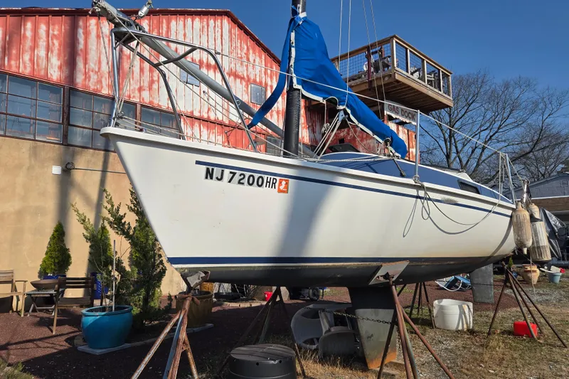 Slide: The Image of 1983 Tillotson-Pearson 21 Freedom sailboat on stands, near rustic building and trees. - 4