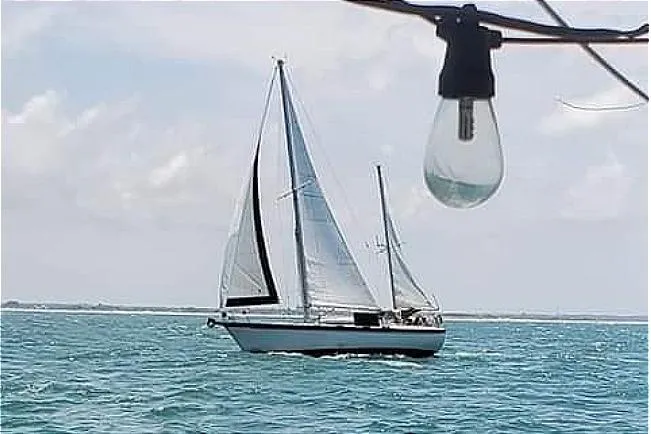 Slide: The Image of 1981 Pearson 424 sailboat on open water with a light bulb in the foreground. - 1
