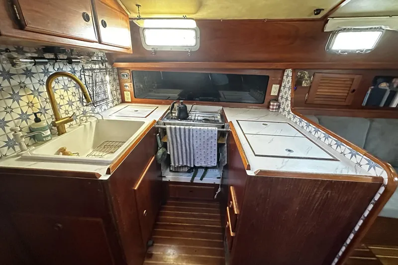 Slide: The Image of 1981 Pearson 424 yacht kitchen with wooden cabinetry, tiled backsplash, and brass faucet. - 17
