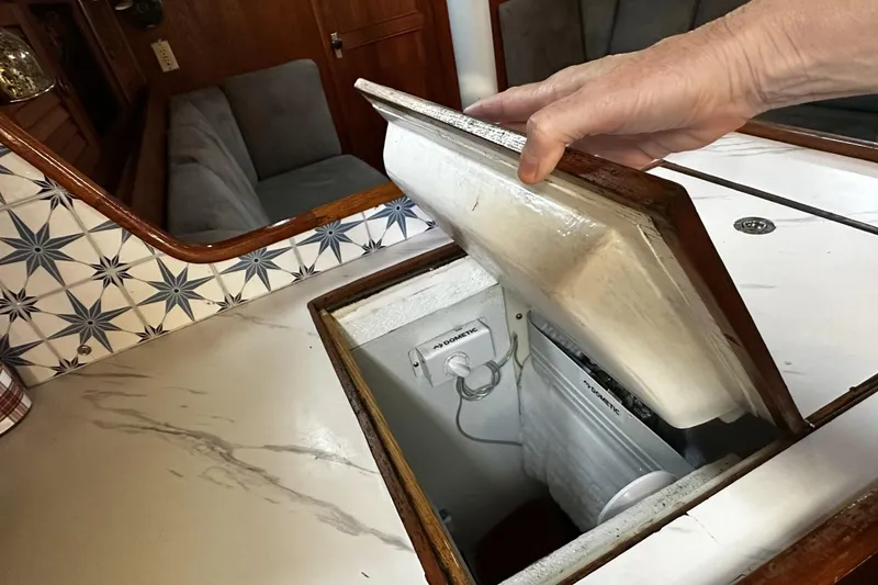 Slide: The Image of Hand opening a storage compartment on a 1981 Pearson 424 sailboat. - 20