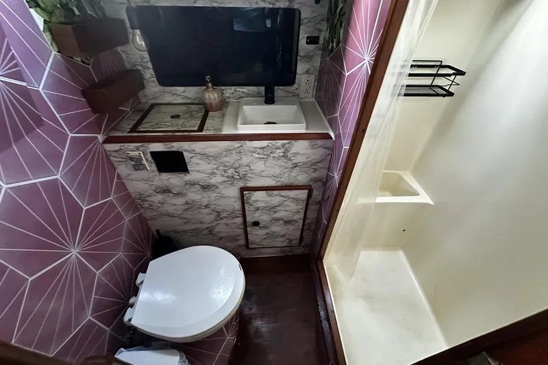 Slide: The Image of Compact bathroom in a 1981 Pearson 424 sailboat with geometric tiles and marble accents. - 29