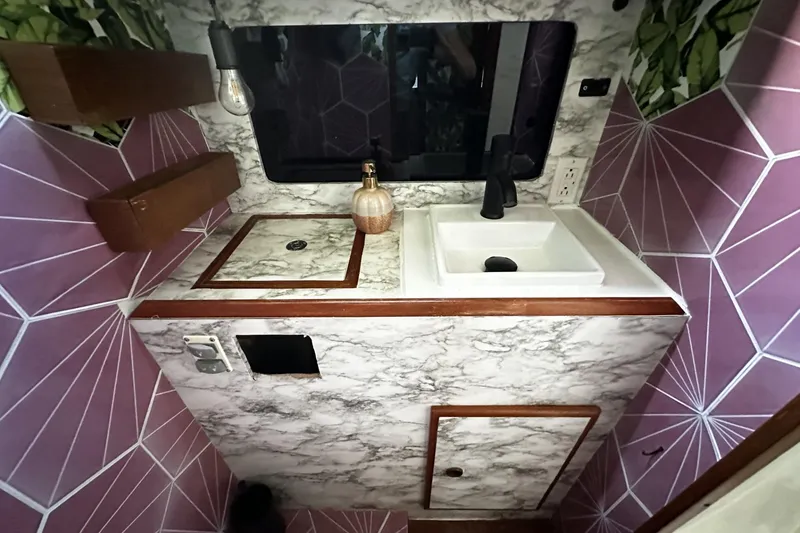 Slide: The Image of Compact 1981 Pearson 424 bathroom with marble countertop, geometric purple tiles, and modern fixtures. - 30