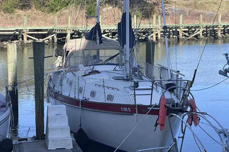 Slide: The Image of 1981 Pearson 424 sailboat docked at a marina, featuring a classic design and safety netting. - 4