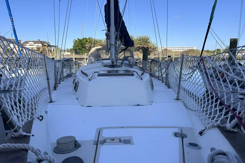 Slide: The Image of 1981 Pearson 424 sailboat deck with netted railings, docked in a marina. - 5
