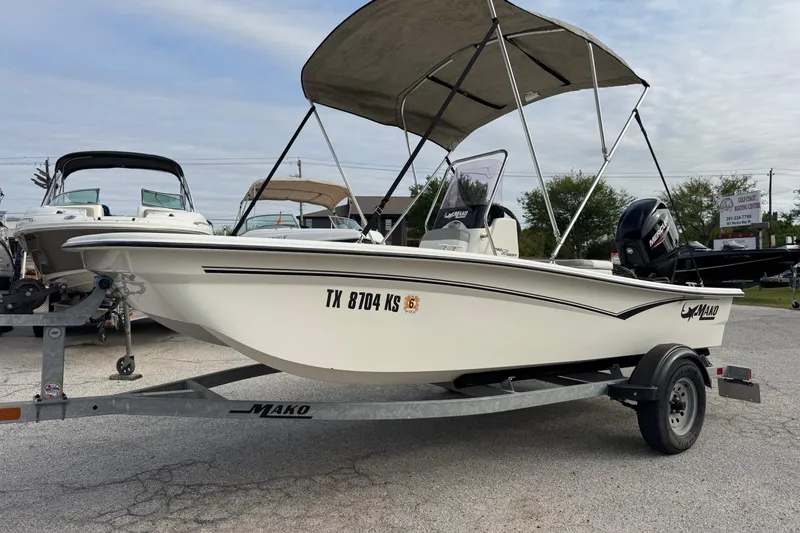 The Image of 2022 Mako Pro Skiff 15 CC boat on trailer with canopy, parked outdoors. - 1