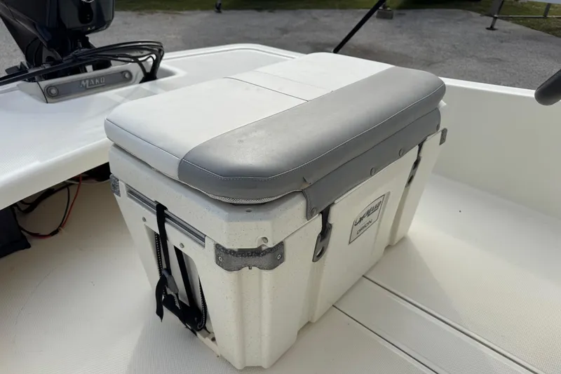 Slide: The Image of 2022 Mako Pro Skiff 15 CC boat with cushioned cooler seat on deck. - 11