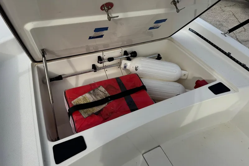Slide: The Image of Open storage compartment in 2022 Mako Pro Skiff 15 CC boat with safety gear. - 18