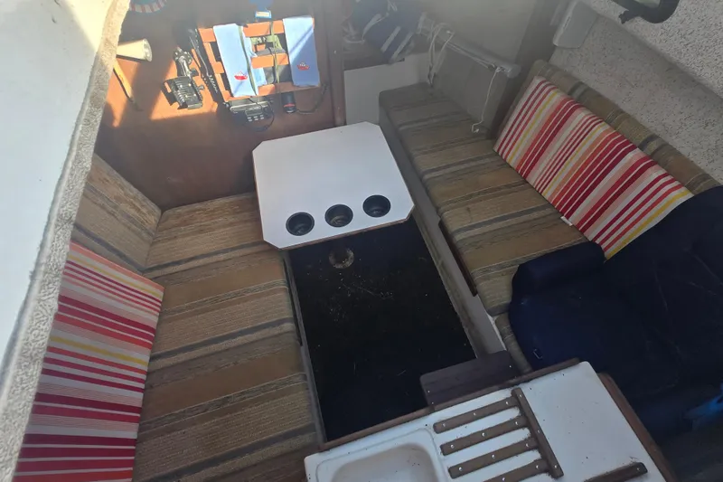 Slide: The Image of Interior of a 1986 Sovereign 24 sailboat with striped cushions and a compact table. - 16