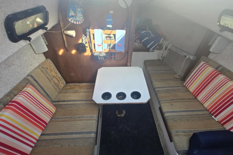 Slide: The Image of Interior of a 1986 Sovereign 24 sailboat with striped cushions and a central table. - 17