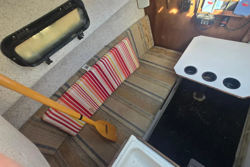 Slide: The Image of Interior of a 1986 Sovereign 24 boat with striped cushions and a wooden oar. - 19