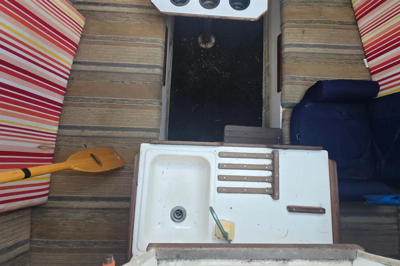 Slide: The Image of Interior of a 1986 Sovereign 24 boat with striped cushions and a small sink. - 20