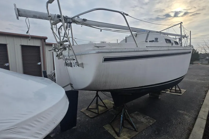 Slide: The Image of 1986 Sovereign 24 sailboat on stands, stored outdoors near storage units, under a cloudy sky. - 3
