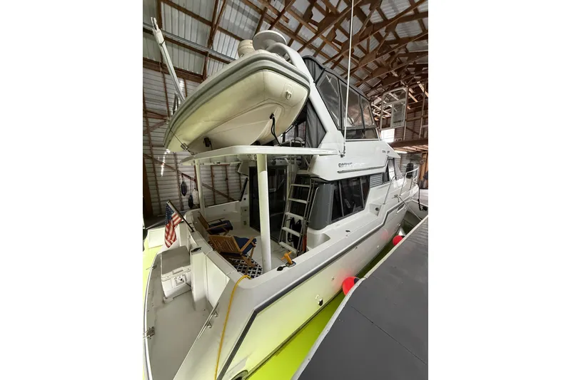 Slide: The Image of 1994 Carver 370 Voyager yacht docked in a covered marina, featuring a spacious deck. - 44