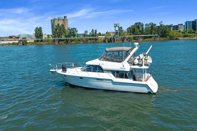 Slide: The Image of 1994 Carver 370 Voyager yacht cruising on a scenic river with industrial backdrop. - 65